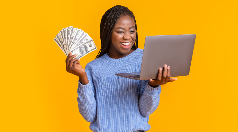Imagem com uma mulher sorrindo segundo em uma mão o notebook e na outra mão várias cédulas de dinheiro.